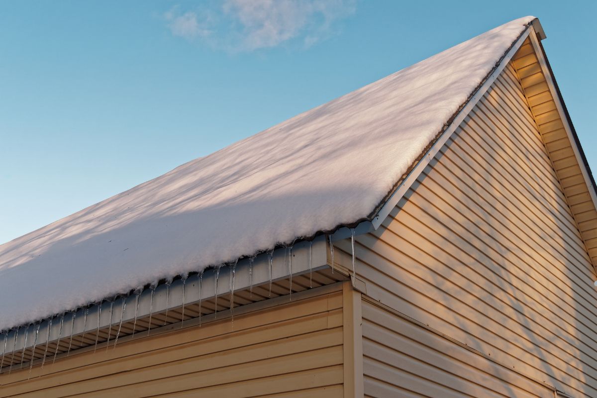 A house with a snow-covered roof, highlighting the importance of a drip edge for proper water drainage.